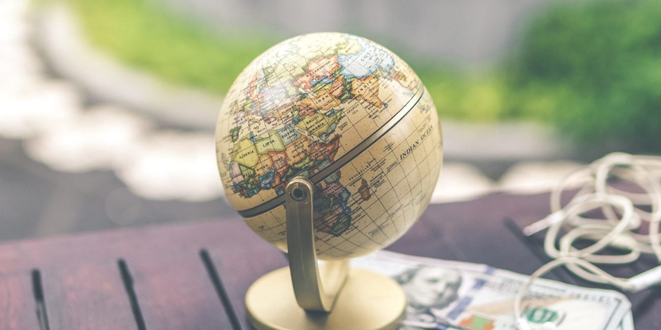 Globus na stole, telefon, pieniądze i słuchawki. Przygotowania do podróży.