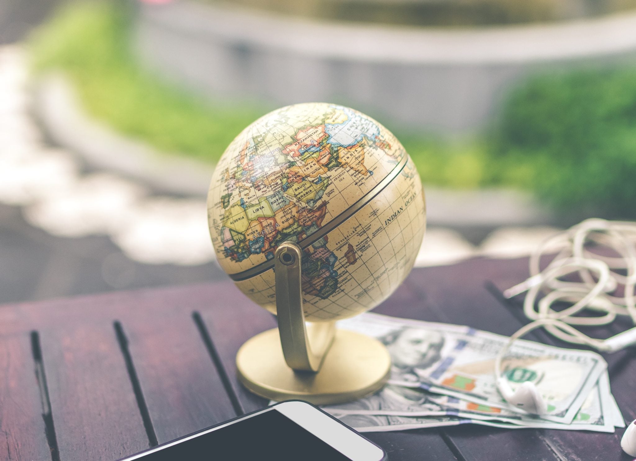 Globus na stole, telefon, pieniądze i słuchawki. Przygotowania do podróży.