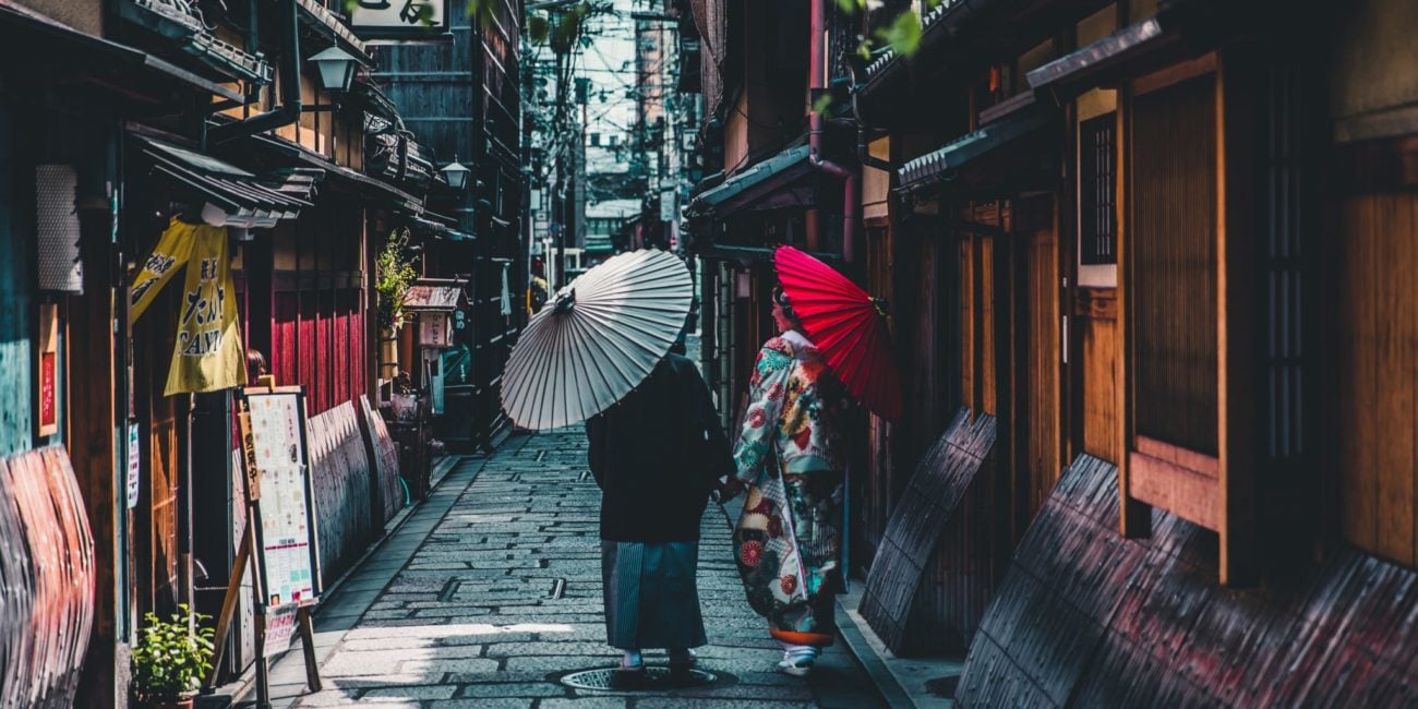 Kobieta i mężczyzna ubrani w kimona, przechadzający się uliczkami z tradycyjnymi domami samurajów w Kioto
